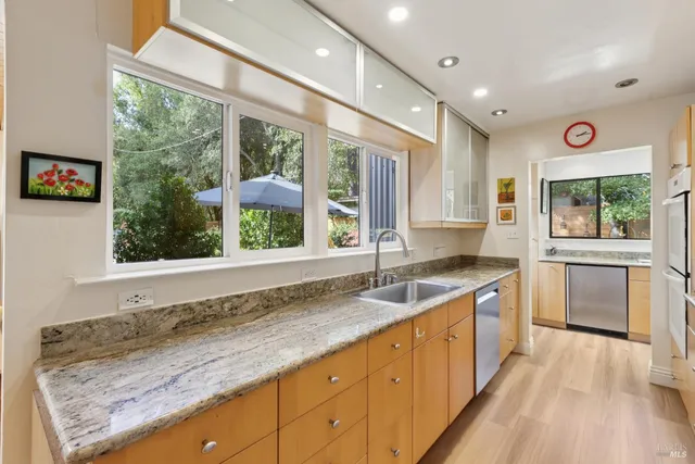 a kitchen with stainless steel appliances kitchen island granite countertop a sink stove cabinets and wooden floor