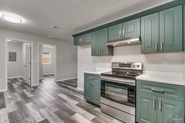 a kitchen with granite countertop a sink a stove and cabinets