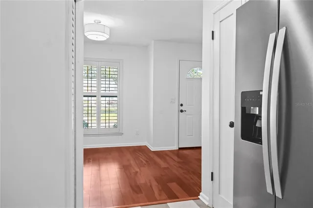 a view of an empty room with wooden floor and a bathroom