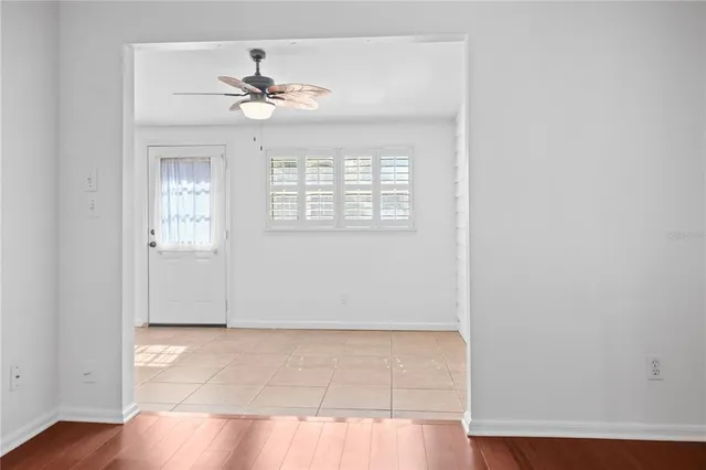 an empty room with wooden floor chandelier fan and windows