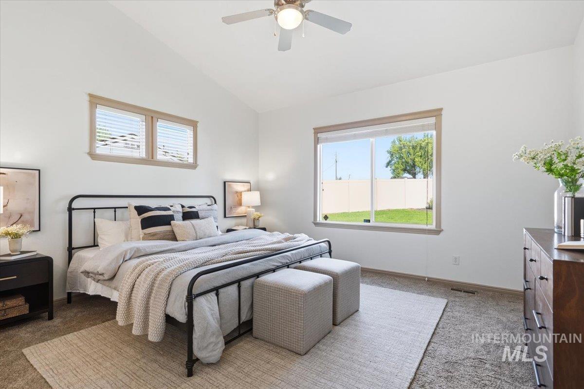 1183 North Buffalo Way Middleton, ID 83644 - Photo 17 of 47 Vaulted ceiling bedroom featuring a ceiling fan, two upper windows, and a large window overlooking the backyard
