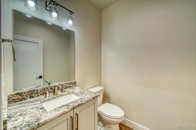 a bathroom with a granite countertop sink a toilet and a mirror