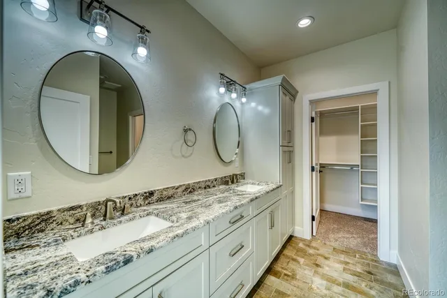 a bathroom with a granite countertop double vanity sink and a mirror
