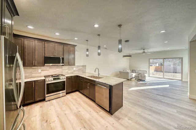 a kitchen with stainless steel appliances granite countertop a sink a stove and a refrigerator