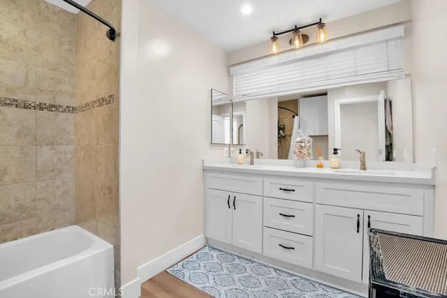 a bathroom with a double vanity sink a mirror a bathtub and shower