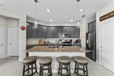 a kitchen with granite countertop a center island a sink stainless steel appliances and cabinets