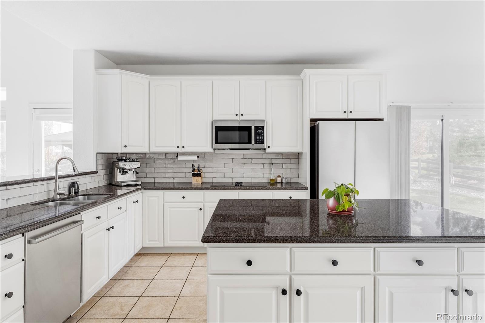6670 Violet Way Arvada, CO 80007 - Photo 14 of 50 a kitchen with stainless steel appliances a sink a stove a refrigerator a counter space and cabinets