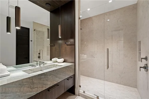 a bathroom with a granite countertop sink a mirror and shower