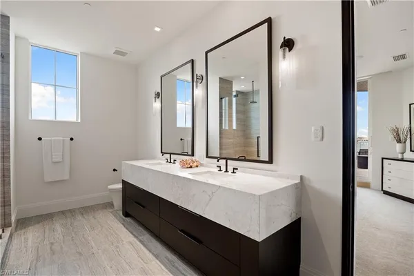 a en suite bathroom with a double vanity sink a mirror and a bathtub