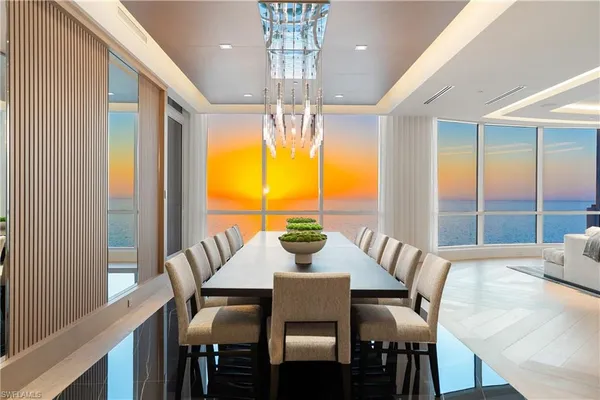 a view of a dining room with furniture a chandelier and large windows