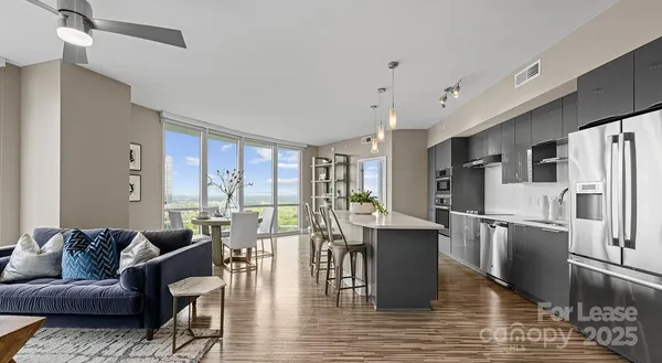 a living room with stainless steel appliances granite countertop furniture wooden floor and a kitchen view