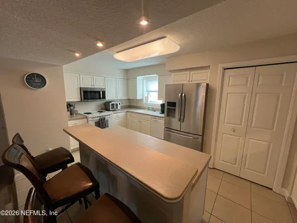 a kitchen with stainless steel appliances a refrigerator a stove a sink dishwasher and white cabinets with wooden floor