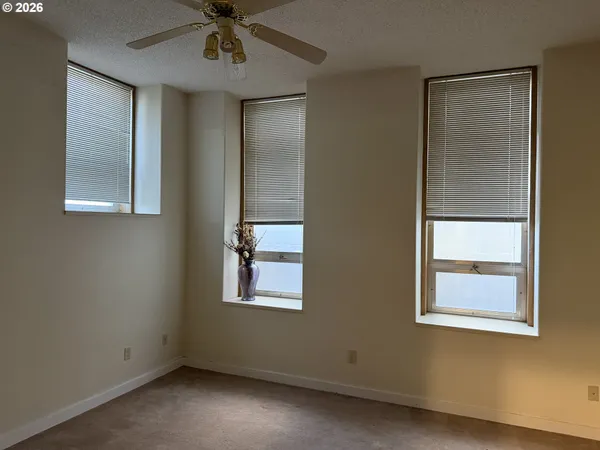 an empty room with windows and fan