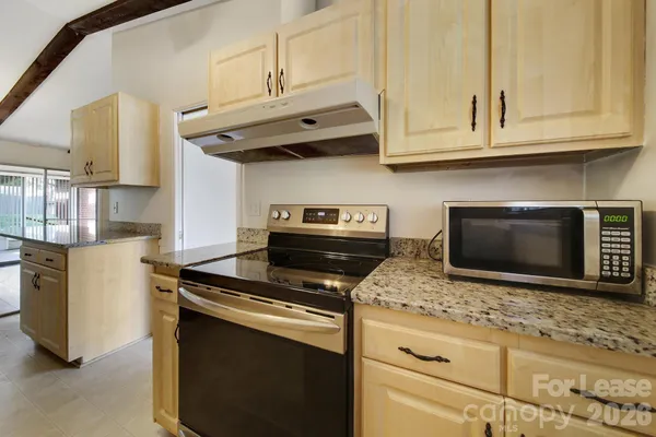 a kitchen with granite countertop white cabinets stainless steel appliances and a counter space