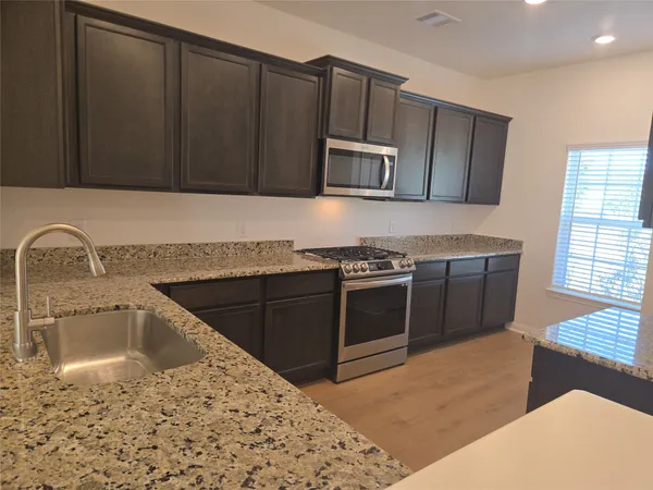 a kitchen with stainless steel appliances granite countertop a sink stove and microwave
