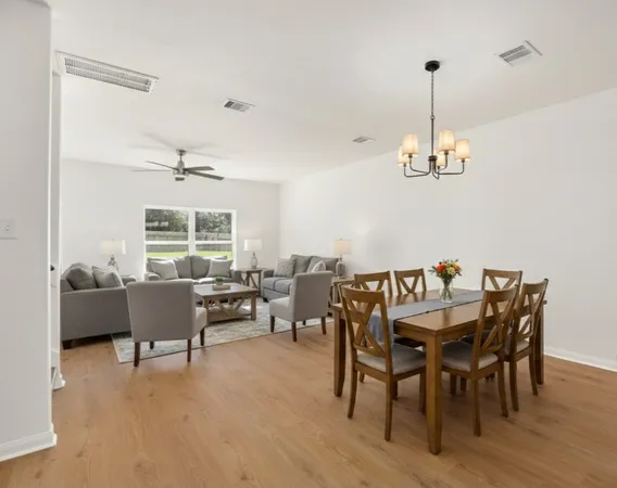 a dining room with furniture a chandelier and wooden floor