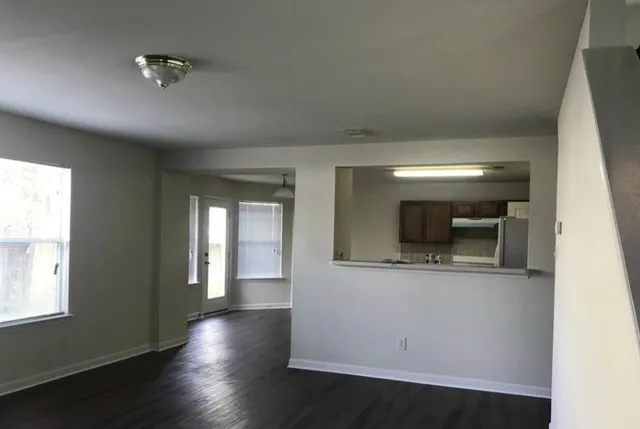 a view of a hallway with wooden floor and a living room