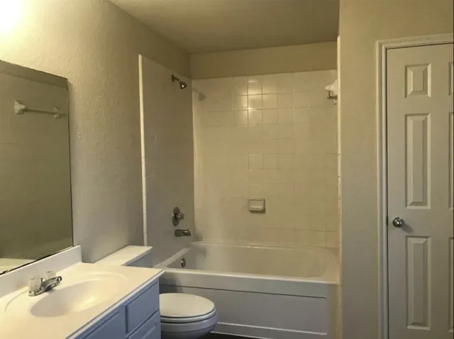 a bathroom with a bathtub shower sink vanity and toilet