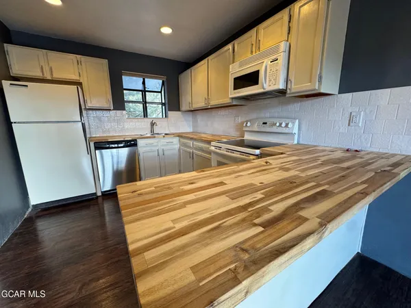 a kitchen with granite countertop wooden cabinets stainless steel appliances and a wooden floor
