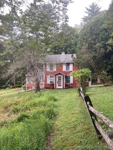 a view of a house with a big yard plants and large trees