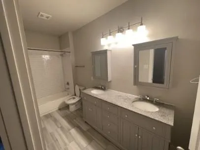 a bathroom with a granite countertop sink toilet a large mirror a shower and a bathtub