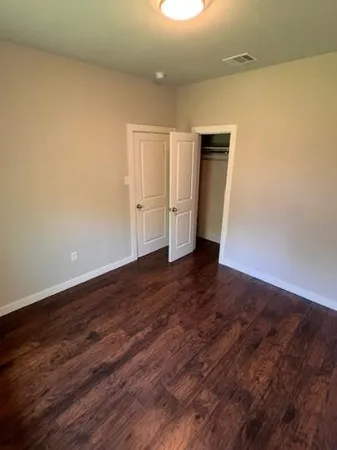 a view of an empty room with closet and a window