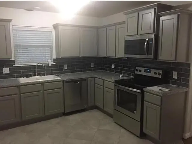 a kitchen with stainless steel appliances granite countertop a sink stove and microwave