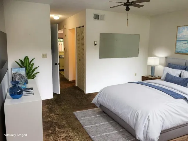 a bedroom with a large bed a rug and potted plant