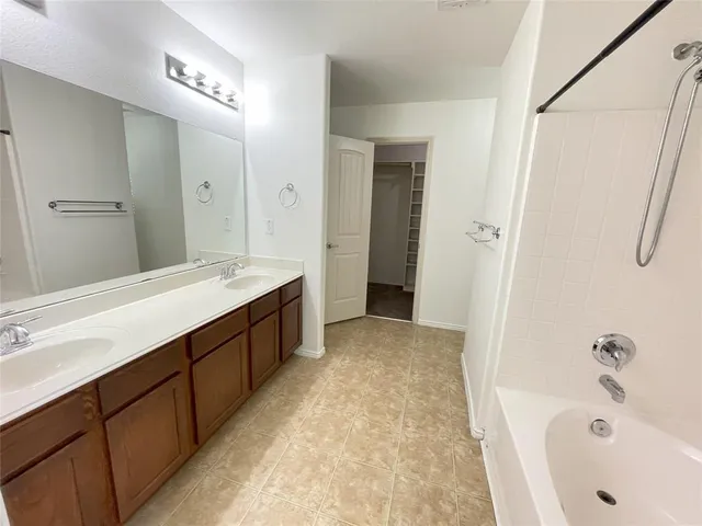 a spacious bathroom with a tub sink shower and mirror