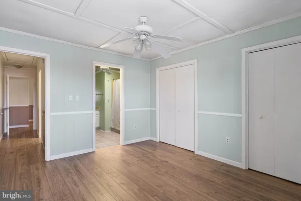 an empty room with wooden floor closet and windows