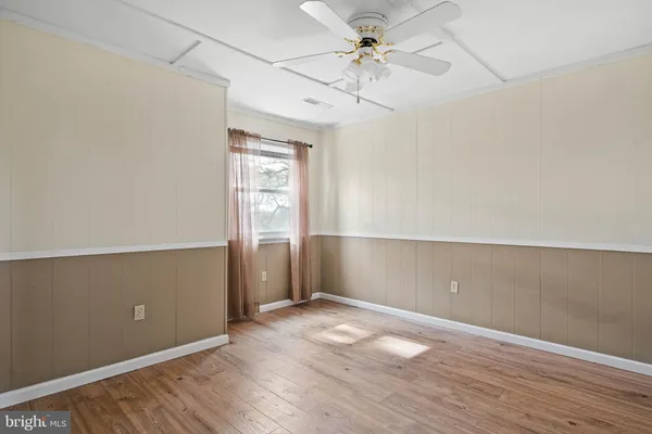 an empty room with wooden floor fan and windows
