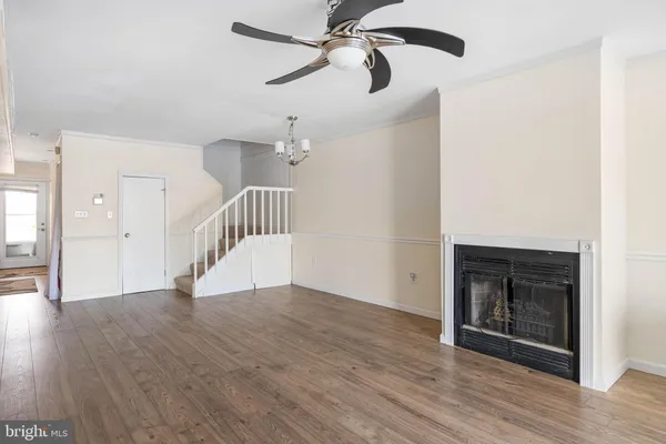a view of an empty room with wooden floor fireplace and a window