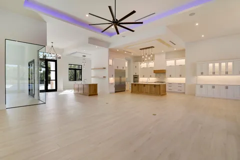 an empty room with windows and chandelier fan