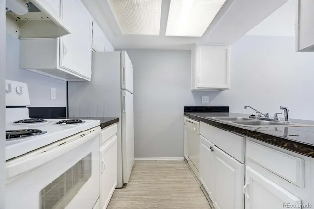a kitchen with granite countertop white cabinets and white appliances