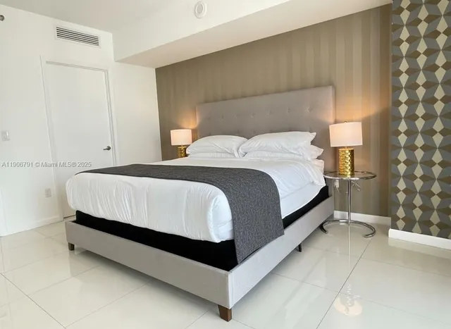 a bed sitting in a bedroom next to a lamp