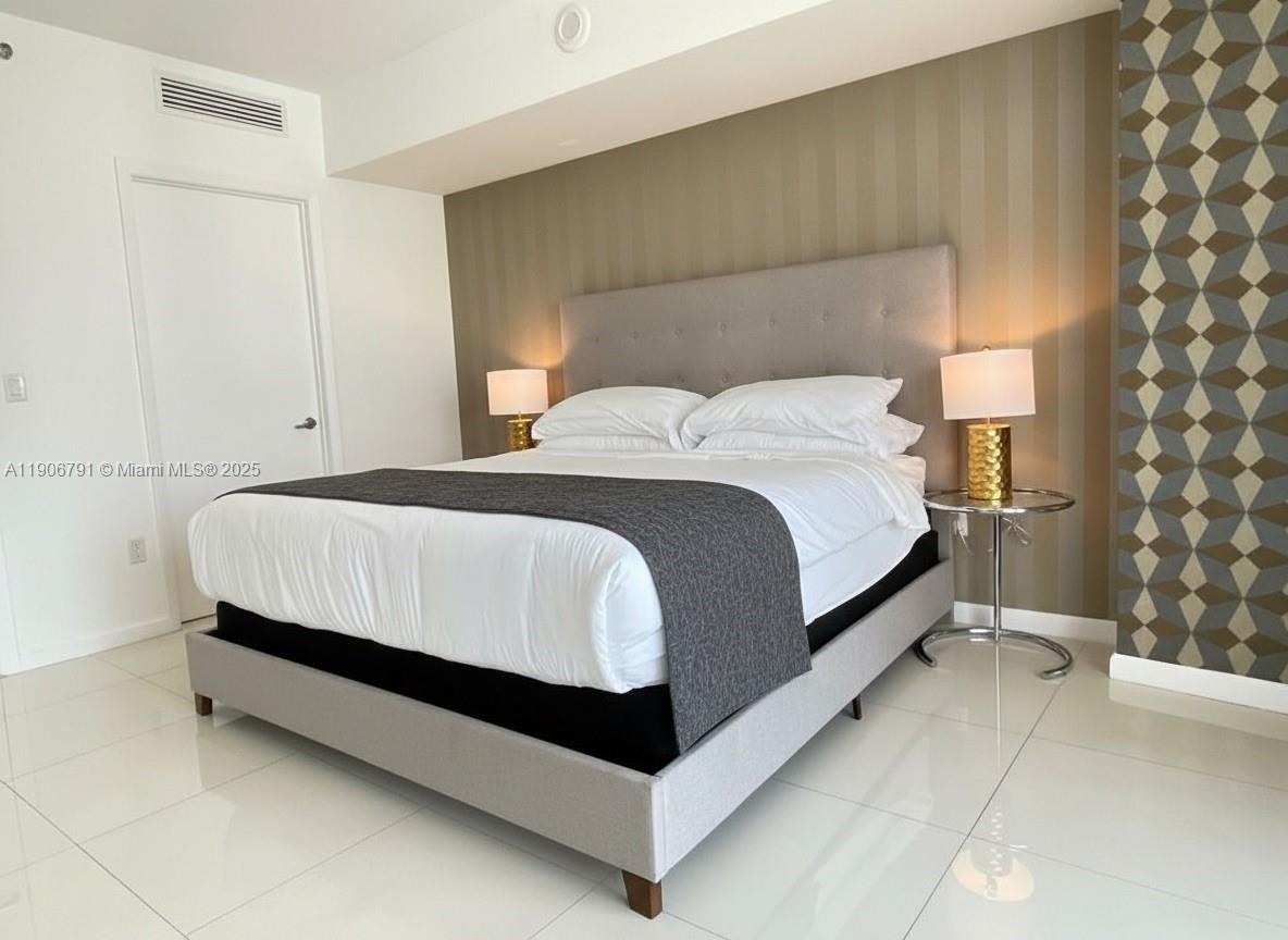 485 Brickell Avenue, Unit 3607 Miami, FL 33131 - Photo 8 of 36 a bed sitting in a bedroom next to a lamp