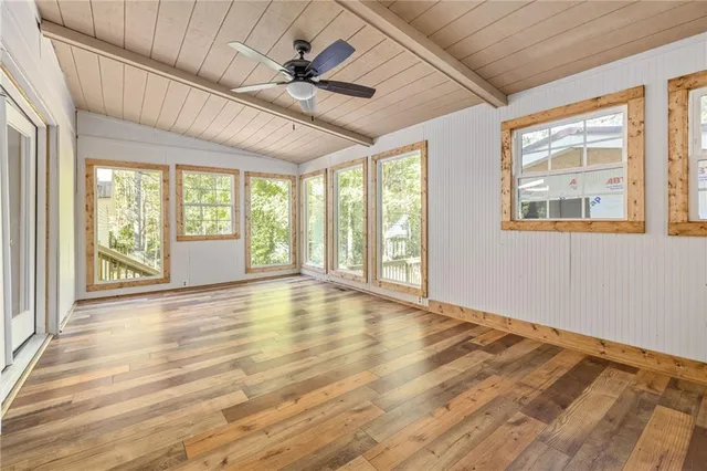 a view of an empty room with a window and wooden floor