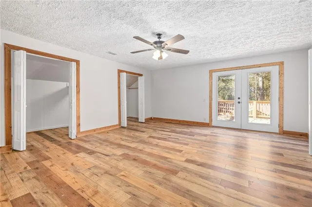 a view of an empty room with window and wooden floor