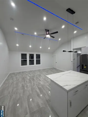 a large kitchen with kitchen island a island wooden floor and a ceiling fan