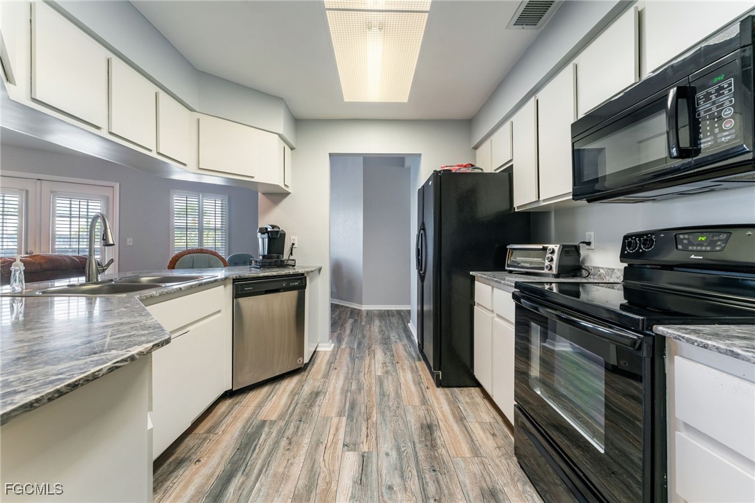 950 Moody Road, Unit 124 North Fort Myers, FL 33903 - Photo 17 of 44 a kitchen with stainless steel appliances granite countertop a refrigerator a stove top oven a sink dishwasher and wooden cabinets