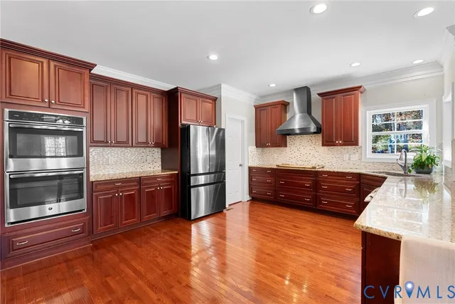 a kitchen with stainless steel appliances granite countertop a refrigerator a stove a sink dishwasher and wooden cabinets with wooden floor