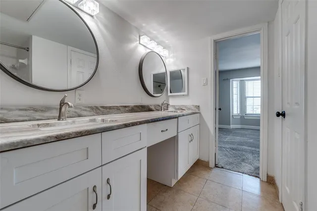a bathroom with a granite countertop double vanity and a mirror