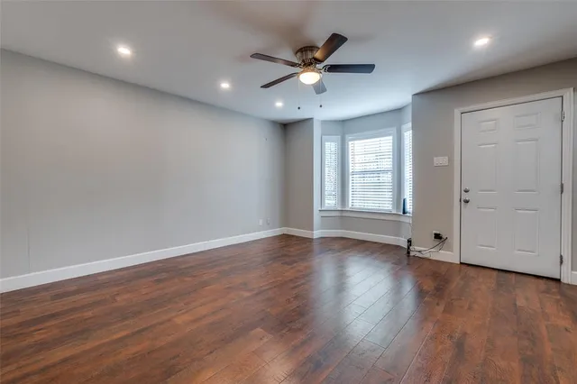 a view of empty room with wooden floor and ceiling fan