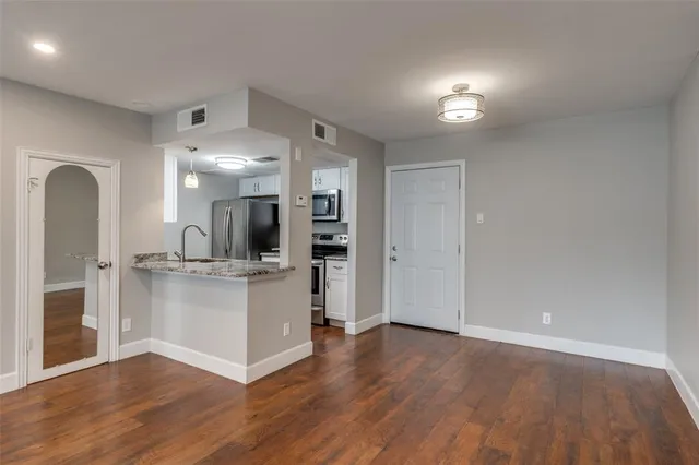 a kitchen with a sink and a stove with wooden floor