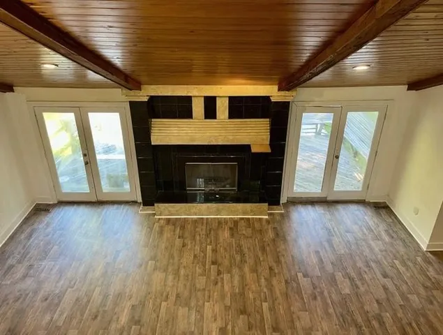 an empty room with wooden floor fireplace and windows