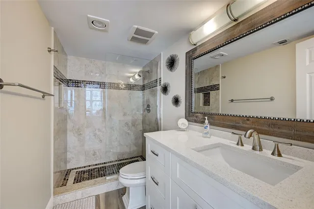 a bathroom with a sink toilet double vanity and shower