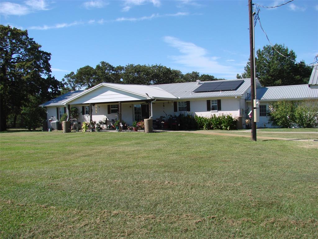 Ranch-style home featuring a front yard, solar panels, a porch, and a metal roof