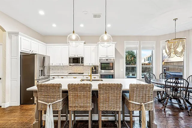 a kitchen with granite countertop stainless steel appliances a dining table and chairs