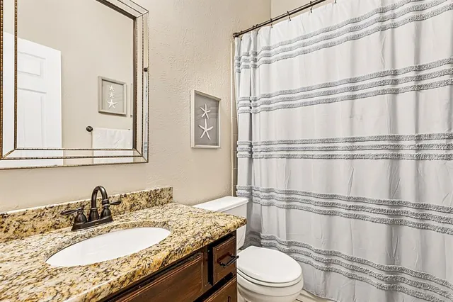 a bathroom with a granite countertop sink toilet mirror and shower