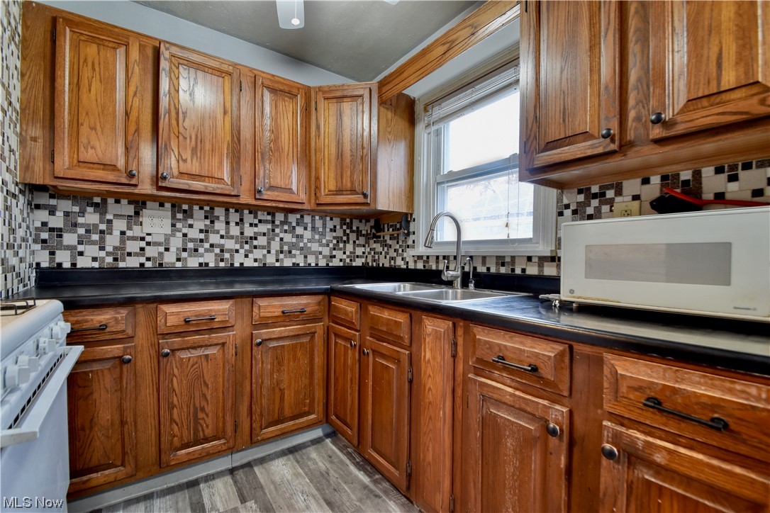 980 Reeve Road Elyria, OH 44035 - Photo 8 of 24 Kitchen with sink, light wood-type flooring, white appliances, and backsplash